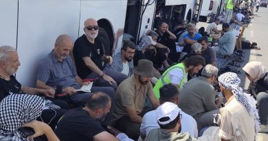 Integrantes del convoy humanitario esperan afuera de uno de los autobuses que los transportaban vía Palestina