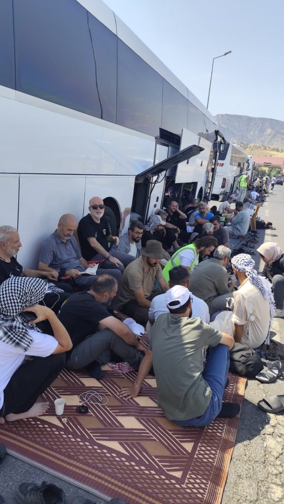 Integrantes del convoy humanitario esperan afuera de uno de los autobuses que los transportaban vía Palestina