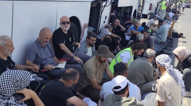 Integrantes del convoy humanitario esperan afuera de uno de los autobuses que los transportaban vía Palestina
