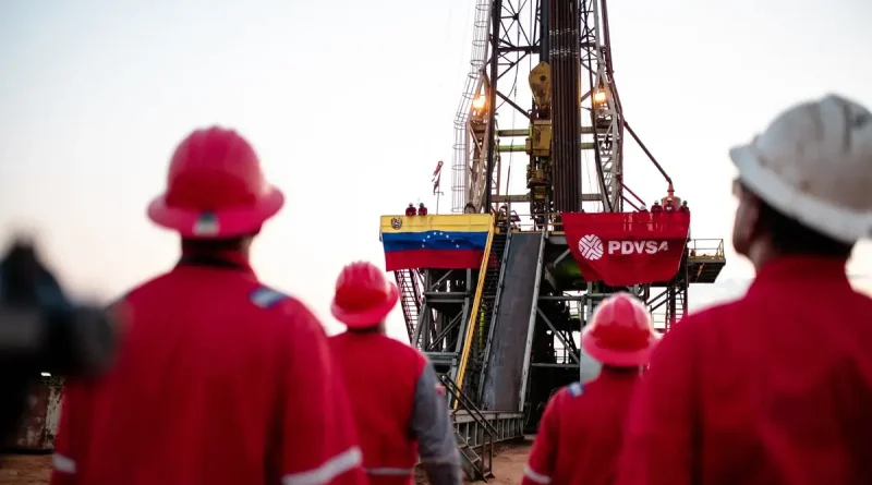Trabajadores de PDVSA en un campo petrolero con un torre con la bandera de PDVSA y de Venezuela